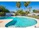 Inviting backyard pool surrounded by lush landscaping, palm trees, and secure fencing for safety at 4418 E Paradise Ln, Phoenix, AZ 85032