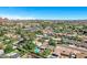 Expansive aerial view showcases a neighborhood with lush landscaping, mature trees, and several homes with private pools under a clear blue sky at 4634 E Wilshire Dr, Phoenix, AZ 85008