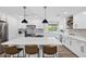 Modern kitchen with white cabinets, a large island with seating, stainless steel appliances, and stylish pendant lighting at 4634 E Wilshire Dr, Phoenix, AZ 85008