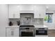 Close-up of the kitchen with stainless steel appliances, white cabinets, and grey backsplash at 4634 E Wilshire Dr, Phoenix, AZ 85008
