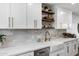 Kitchen with farmhouse sink, bronze fixtures, white cabinets, and open wood shelves at 4634 E Wilshire Dr, Phoenix, AZ 85008