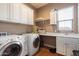 Well-organized laundry room with white cabinetry, washer, dryer, and counter space for folding at 6535 W Gold Mountain Pass, Phoenix, AZ 85083