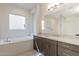 Well-lit bathroom featuring a soaking tub, dark wood cabinets, and granite countertops at 6728 N 190Th Dr, Waddell, AZ 85355