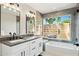 Stylish bathroom with double sinks, modern fixtures, a soaking tub, and a window overlooking a private outdoor space at 6800 E Exeter Blvd, Scottsdale, AZ 85251