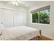 Cozy bedroom with a ceiling fan, white closet doors, and a large window offering views of lush greenery at 6800 E Exeter Blvd, Scottsdale, AZ 85251