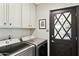 Functional laundry room with modern appliances, white cabinets, and a unique black door with a diamond-patterned window at 6800 E Exeter Blvd, Scottsdale, AZ 85251