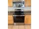 Close-up of stainless steel oven and microwave with light wood cabinetry and tiled floor at 7176 W Blackhawk Dr, Glendale, AZ 85308