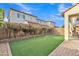 Backyard with artificial grass, brick pavers, and flowering shrubs bordering a covered patio, ideal for relaxation at 7234 W Aire Libre Ave, Peoria, AZ 85382