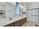 Bathroom featuring double sinks, a large mirror, a walk-in shower with glass doors at 7234 W Aire Libre Ave, Peoria, AZ 85382
