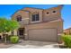 Charming two-story home featuring tan stucco, a two-car garage, manicured landscaping, and a blue sky at 8879 W Cameron Dr, Peoria, AZ 85345