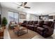 Spacious living room featuring a comfortable leather sofa, ceiling fan, and lots of natural light at 8879 W Cameron Dr, Peoria, AZ 85345
