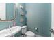 Stylish bathroom features a pedestal sink, decorative shelves, and blue textured wallpaper at 9936 E Revolution Dr, Mesa, AZ 85212