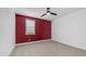 Neutral carpet and a red accent wall define this comfortable and airy bedroom at 9936 E Revolution Dr, Mesa, AZ 85212
