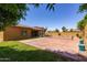 Expansive backyard featuring a tennis court, lush grass, and a covered patio with comfortable seating and table at 10402 E Starion Ave, Mesa, AZ 85212