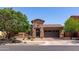 This single-Gathering home has stone accents, a tile roof, mature landscaping, and a wrought iron gate at the front entry at 10402 E Starion Ave, Mesa, AZ 85212