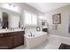 Luxurious bathroom featuring a soaking tub, dual sinks, and plantation shutters at 10402 E Starion Ave, Mesa, AZ 85212