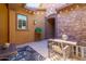 A cozy covered patio with a dining set, comfortable seating, decor, and stone accents at 10402 E Starion Ave, Mesa, AZ 85212