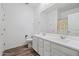 Well-lit bathroom features a double sink vanity, a large mirror and wood-look floors at 12416 W Midway Ave, Glendale, AZ 85307