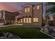 Beautiful home exterior showcasing a covered patio, manicured lawn, and desert landscaping during twilight at 13446 S 186Th Ave, Goodyear, AZ 85338