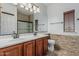 Bathroom with a dual sink vanity, stone accents, and a shower with glass doors at 13446 S 186Th Ave, Goodyear, AZ 85338
