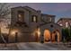 Inviting two-story home with warm exterior lighting, arched entryway, and desert landscaping at 13446 S 186Th Ave, Goodyear, AZ 85338