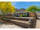 Charming home featuring attractive landscaping, a stone retaining wall, and lush green trees against a mountain backdrop at 1527 E Sunnyslope Ln, Phoenix, AZ 85020