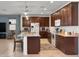 Beautiful kitchen featuring dark wood cabinetry, a granite-topped island, stainless steel appliances, and tiled flooring at 15704 W Taylor St, Goodyear, AZ 85338