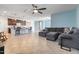 Open-concept living room featuring tile floors, modern ceiling fan, and comfortable gray sofa and breakfast bar seating at 15704 W Taylor St, Goodyear, AZ 85338