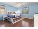 Serene main bedroom with a wood-accented headboard, soft blue walls and a bright window at 15704 W Taylor St, Goodyear, AZ 85338