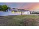Exterior shot of home shows desert landscape and a mountain backdrop under an orange and purple sky at 1644 W Thunderbird Rd, Phoenix, AZ 85023