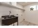 Laundry room featuring a stainless steel sink, shelving, and light-colored floors at 1644 W Thunderbird Rd, Phoenix, AZ 85023