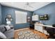 This home office offers a comfortable work space with a stylish rug and blue accent wall for a modern touch at 17611 W Ingleside Dr, Surprise, AZ 85374