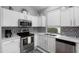 Updated kitchen with stainless steel appliances, white cabinets, and a modern backsplash at 17611 W Ingleside Dr, Surprise, AZ 85374