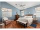 Relaxing main bedroom with blue walls, wood floors, and large windows at 17611 W Ingleside Dr, Surprise, AZ 85374