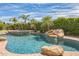 Backyard features a sparkling pool with a rock waterfall, palm trees, and lush greenery at 1805 W Dusty Wren Dr, Phoenix, AZ 85085