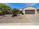 Inviting single-story home featuring a two-car garage and desert landscaping with mature palms at 20900 N Vista Trl, Surprise, AZ 85387