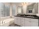 Bright bathroom featuring a double vanity, a soaking tub, and a glass block window at 2139 S Granite St, Gilbert, AZ 85295