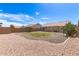 An expansive backyard with a well-kept lawn, desert landscaping, and a covered patio for outdoor entertaining at 30587 N Maple Chase Dr, San Tan Valley, AZ 85143