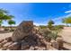 A large rock sign marks the entrance of the community, framed by mature desert trees and vegetation at 30587 N Maple Chase Dr, San Tan Valley, AZ 85143