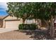 Well-maintained home exterior with a two-car garage, desert landscaping, and a mature shade tree at 30587 N Maple Chase Dr, San Tan Valley, AZ 85143