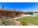 Spacious backyard with green lawn, a sparkling pool, and covered patio adjacent to the brick house at 3131 E Las Rocas Dr, Phoenix, AZ 85028