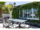 Close-up of backyard patio featuring glass top outdoor dining table, chairs, and lush greenery at 338 W Encanto Blvd, Phoenix, AZ 85003