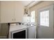 Bright laundry room features modern washer and dryer, storage cabinets, and access to the outdoors at 338 W Encanto Blvd, Phoenix, AZ 85003