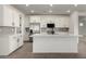 Stylish kitchen boasts white cabinets, stainless steel appliances, a spacious island with seating, and wood-look flooring at 4034 W Nora Dr, San Tan Valley, AZ 85144