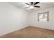 A carpeted bedroom with neutral walls, a ceiling fan, and a window view at 4107 W Campo Bello Dr, Glendale, AZ 85308
