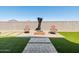Outdoor firepit with two chairs set on a brick patio surrounded by artificial turf at 41800 W Sonoran Trl, Maricopa, AZ 85138