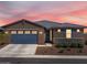 Charming single-story home with a blue garage door, stone accents, and desert landscaping at sunset at 41800 W Sonoran Trl, Maricopa, AZ 85138