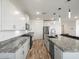 Modern kitchen featuring white cabinetry, granite countertops, stainless steel appliances, and a kitchen island at 41800 W Sonoran Trl, Maricopa, AZ 85138