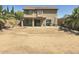 Backyard featuring large dirt area, covered patio, block wall fence, trash bins, and trees at 42435 W Desert Fairways Dr, Maricopa, AZ 85138
