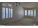 Inviting living room featuring carpet flooring, large windows with plantation shutters and neutral paint at 42435 W Desert Fairways Dr, Maricopa, AZ 85138